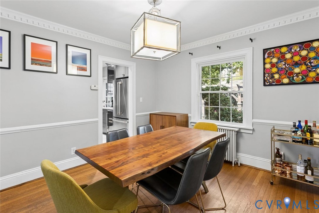 Hardwood flooring, crown molding, chair rail molding, a large framed window, and a rectangular ceiling light fixture