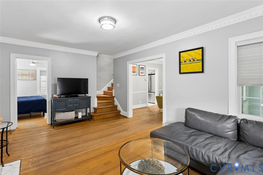Hardwood flooring, crown molding, white trim, recessed lighting, and a visible staircase