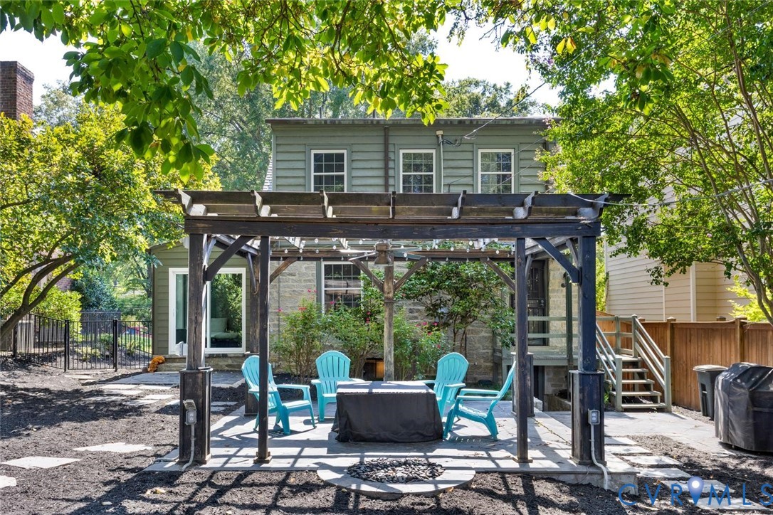 Backyard featuring a wood pergola over a stone patio, a stone house exterior, and a secondary structure with green siding