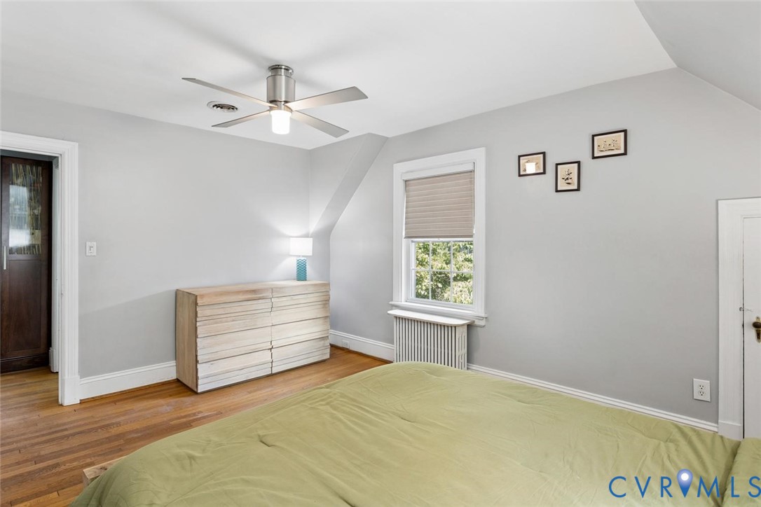 Hardwood flooring, sloped ceiling, window with pleated shade, ceiling fan
