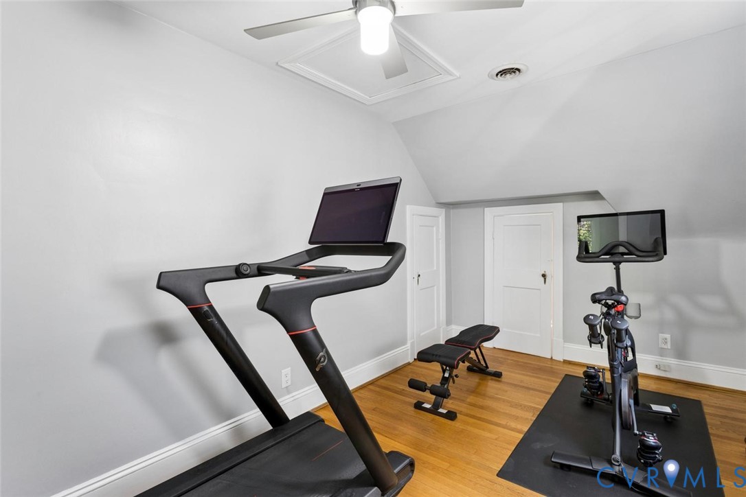Hardwood flooring with a matte finish, sloped ceiling, and a ceiling fan with integrated lighting