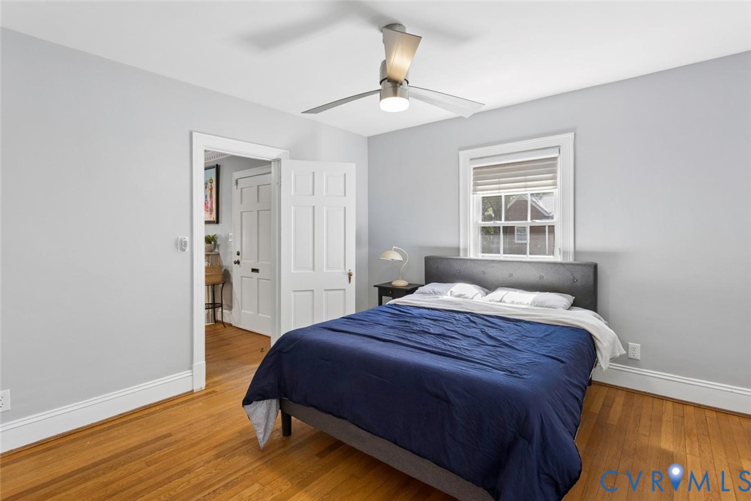 Hardwood flooring, painted walls, ceiling fan, white trim, and a window with blinds