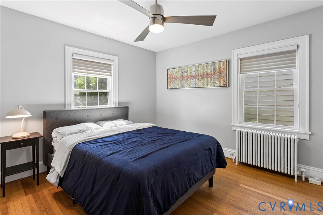 Wood-finish flooring, white trim, and a ceiling fan with integrated lighting