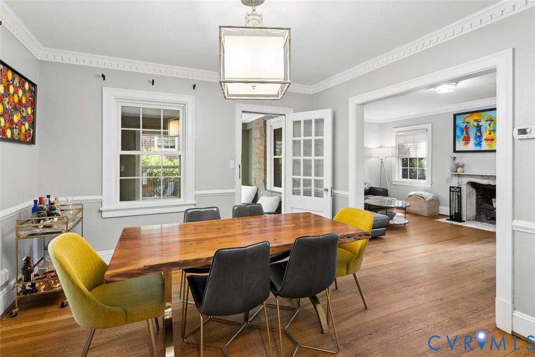Wood-finish flooring, crown molding, chair rail molding, square-frame chandelier, and window with grid muntins
