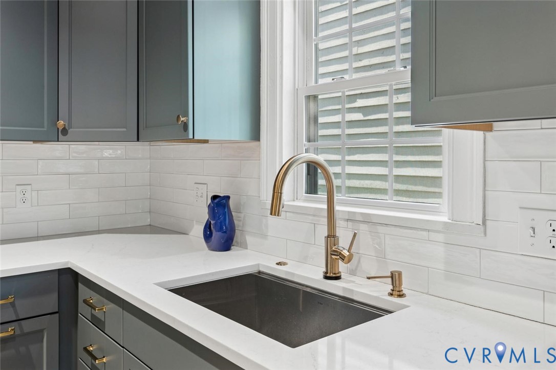 White subway tile backsplash, white countertop, stainless steel undermount sink, and bronze-finish faucet