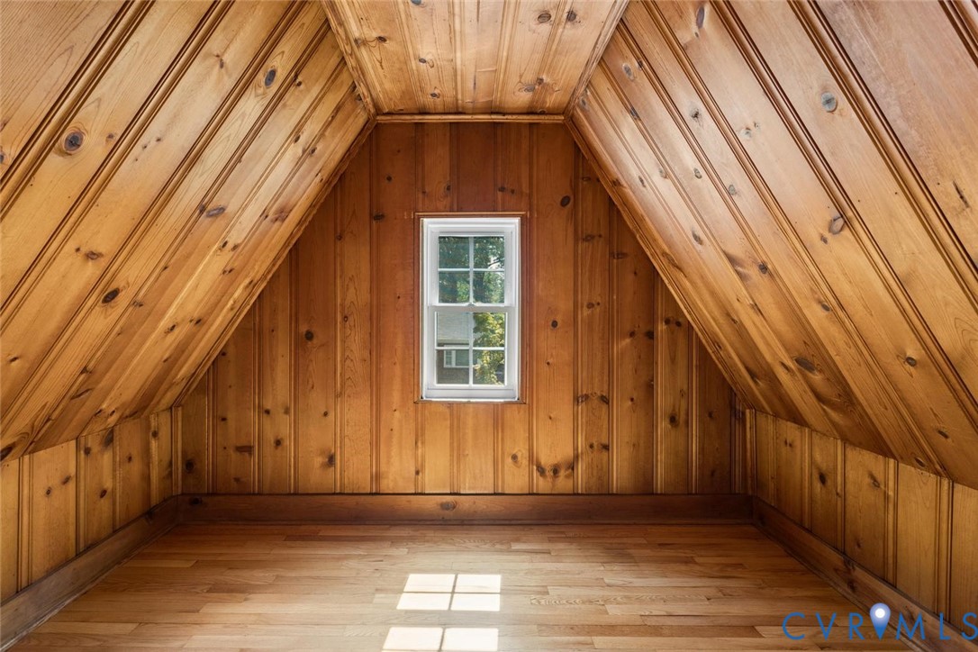 Paneled wood walls and ceiling, hardwood flooring, and a single window