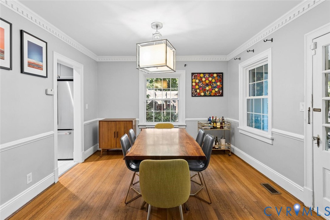 Hardwood flooring, crown molding, double-hung windows, and a built-in refrigerator in an adjoining space