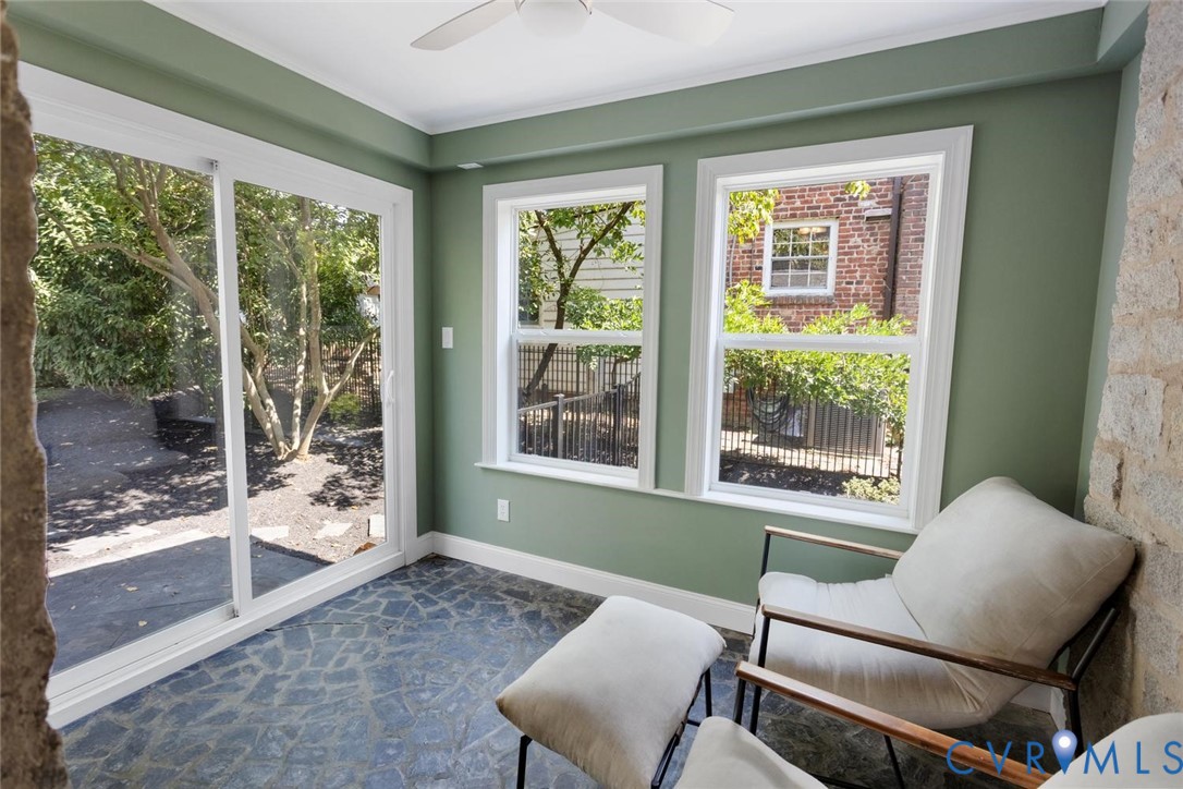 Sunroom featuring a ceiling fan, sliding glass door, multiple windows, and irregular stone flooring