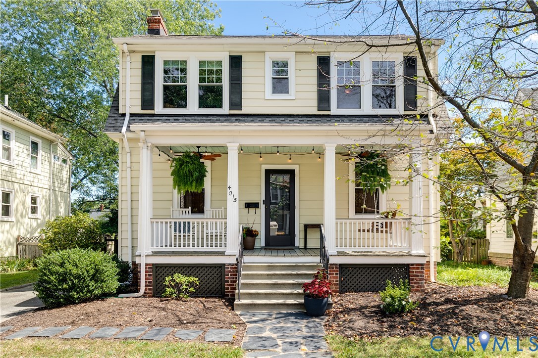 Two-story facade with light-colored siding, black shutters, and a covered front porch