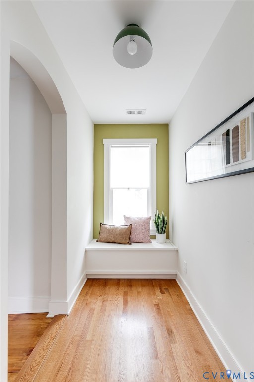 Hardwood flooring, arched doorway, built-in window seat, recessed window, and a contemporary ceiling light fixture