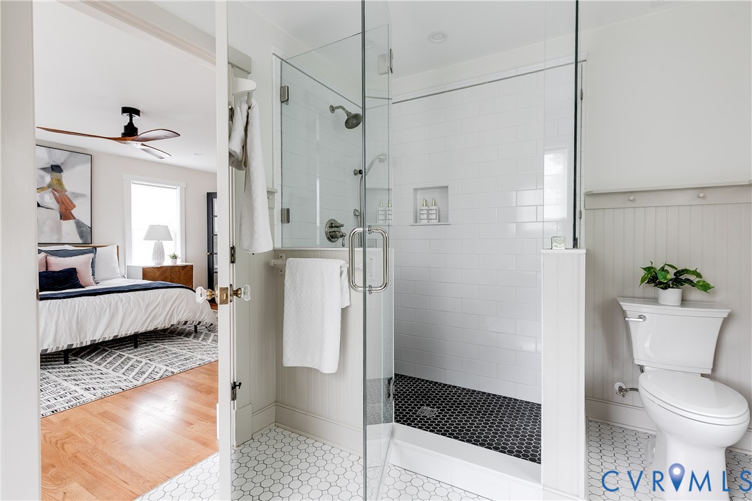 Glass-enclosed shower with subway tile surround and black hexagon tile flooring