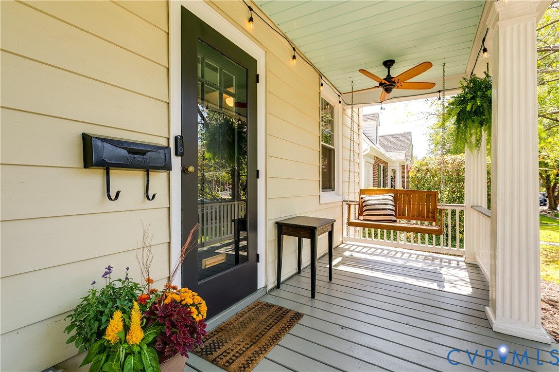 Covered front porch featuring a ceiling fan, string lighting, and white columns