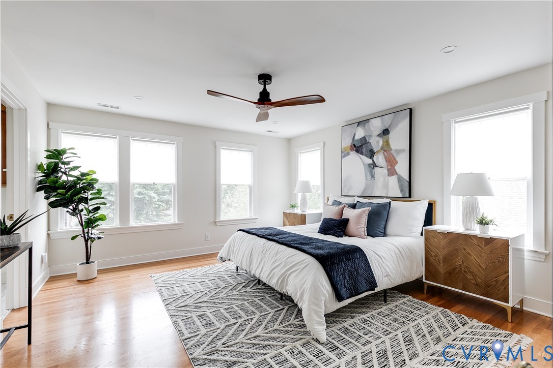 Hardwood flooring, recessed lighting, four large windows, and a ceiling fan with wood-finish blades