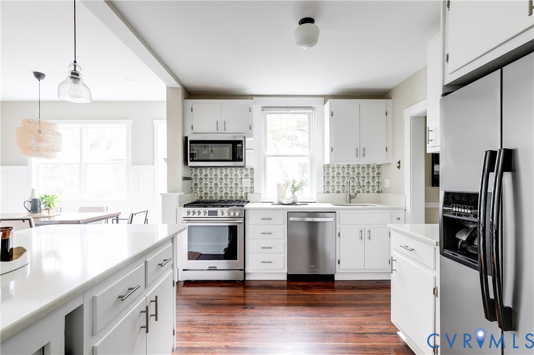 Kitchen featuring white cabinetry, stainless steel appliances, and hardwood flooring