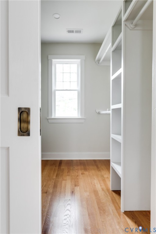 Recessed ceiling lighting, wood flooring, built-in shelving, and a window with grid pattern