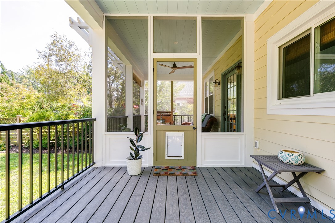 Expansive porch featuring composite decking, black metal railings, and a screened door with a built-in pet access panel