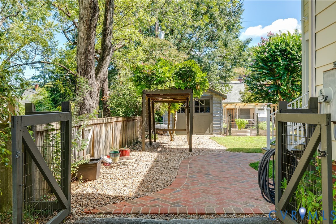 Brick pathway leading to a gravel patio with an arbor