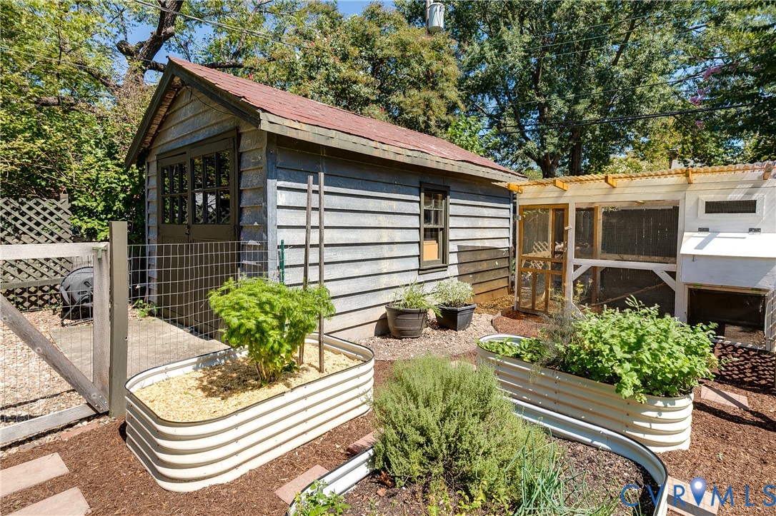 Wood-sided shed with a gable roof, adjacent to a structured enclosure with a corrugated roof