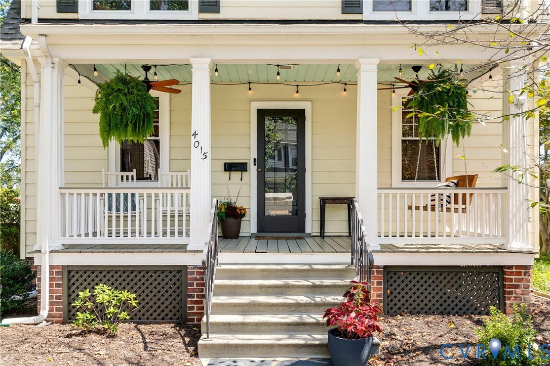 Welcoming front porch with white railings, a black entry door, and concrete steps