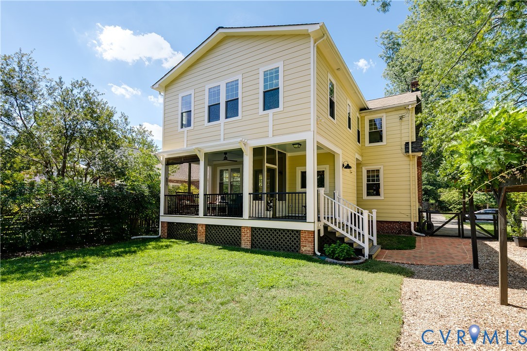 Yellow siding exterior with a screened porch and white railing, brick foundation, and a gravel pathway