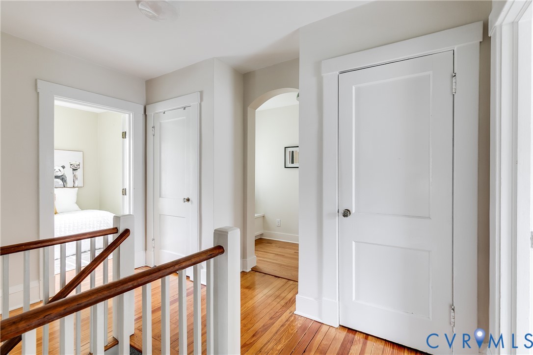 Hardwood flooring throughout, white painted trim, white paneled doors, and an arched doorway