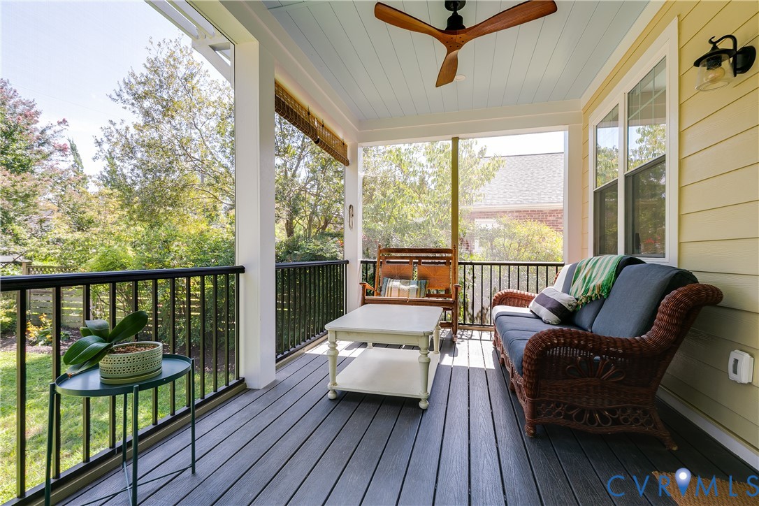 Screened porch with composite decking, white architectural columns, a light blue beadboard ceiling, and a ceiling fan
