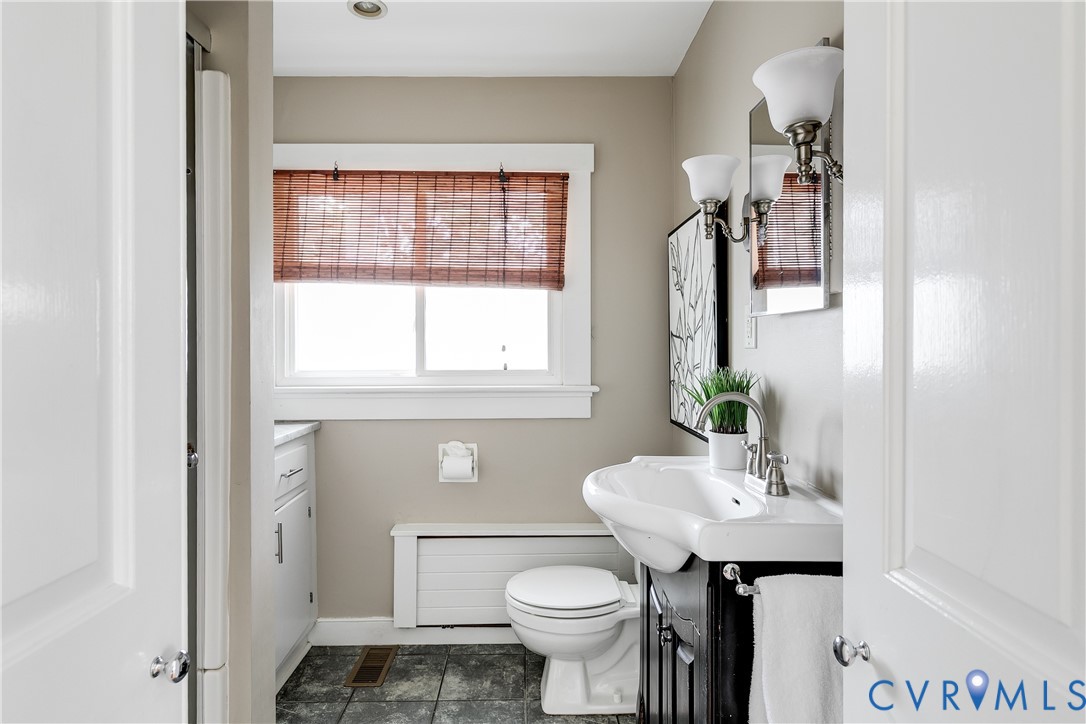Recessed ceiling light, white window trim, dual-sconce wall lighting, and dark wood vanity sink