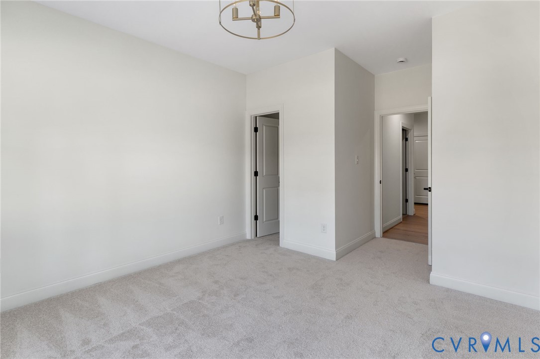 Neutral color palette with light gray carpeting and white walls, complemented by a contemporary circular chandelier