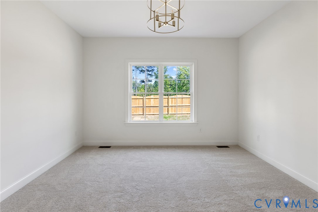White interior walls, light gray carpeting, and a central window with exterior fencing