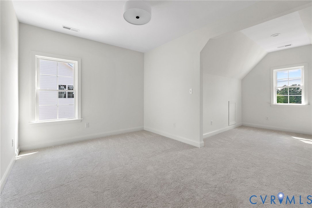 Carpeted flooring, white walls, two windows, and a flush mount ceiling light fixture