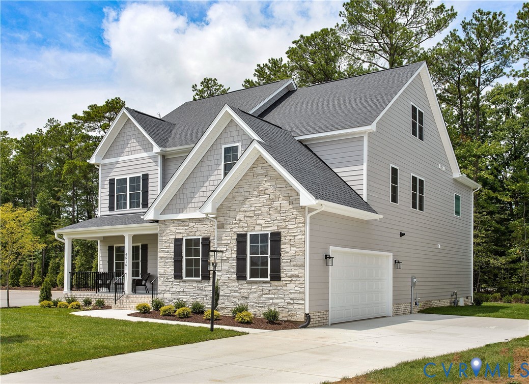 Two-story exterior with stone and siding accents, prominent front porch with white columns, attached garage, and a concrete driveway