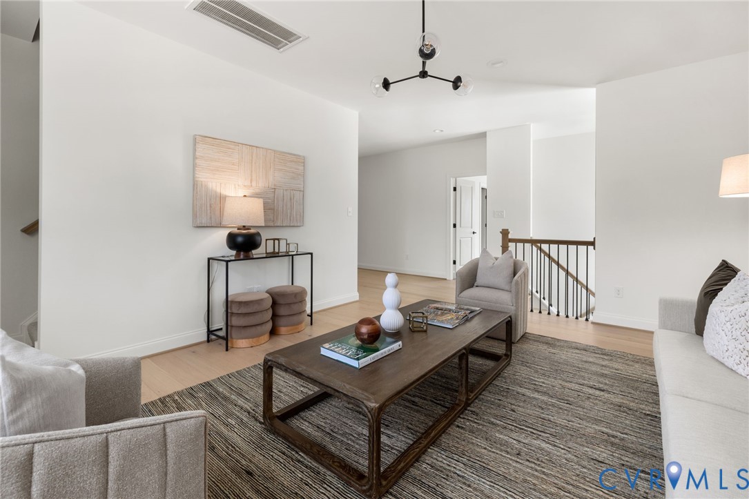 Recessed lighting, wood-finish flooring, white walls, black metal spindle railing, and a contemporary ceiling fixture