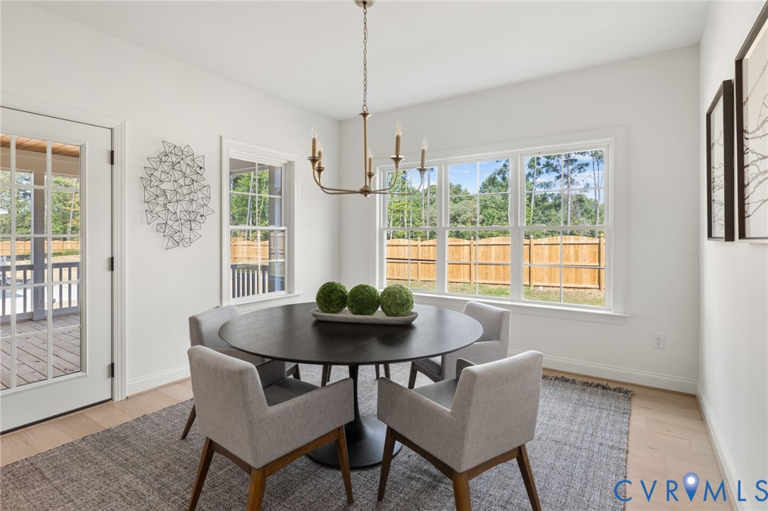 Multiple large windows, French doors, light wood-finish flooring, and a candelabra chandelier