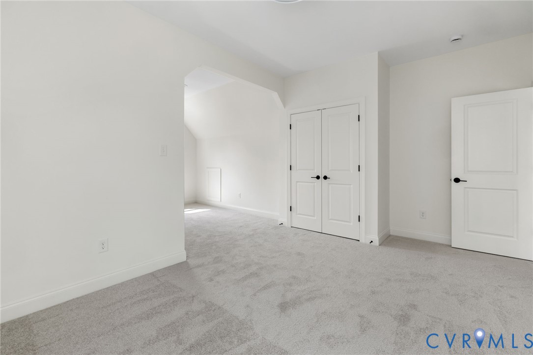Expansive room with neutral carpeting and a fresh white color palette