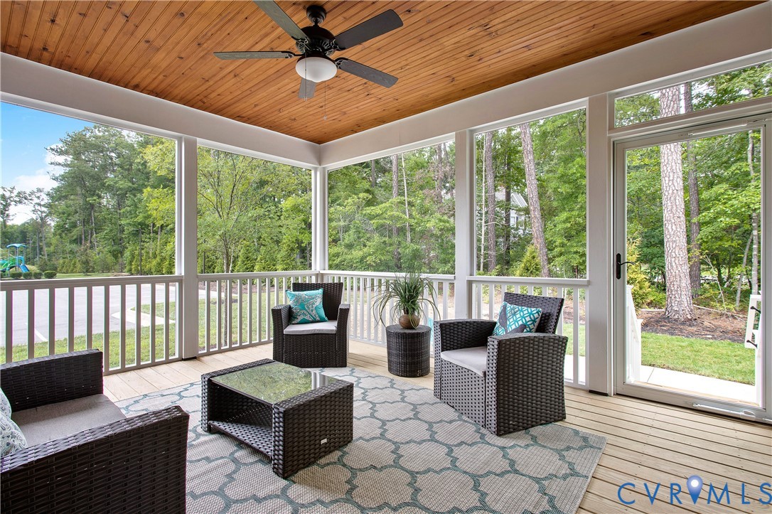 Screened porch featuring a natural wood plank ceiling, an overhead fan with integrated lighting, wood-finish flooring, and white railing