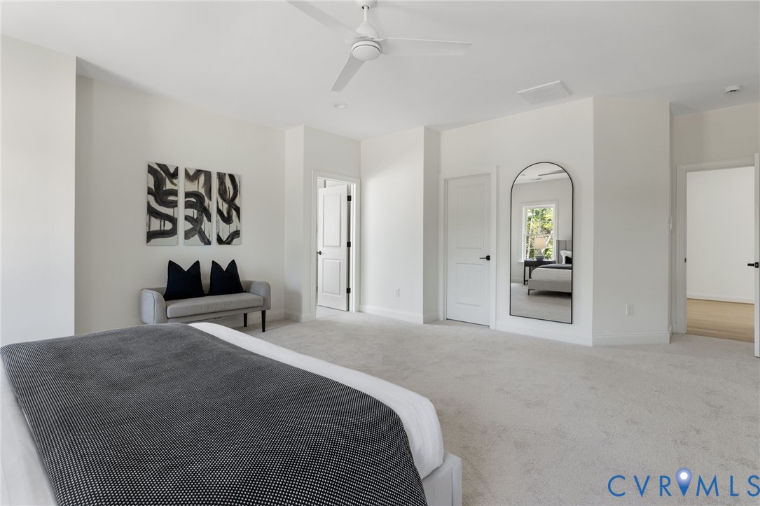 Spacious room featuring light-colored carpeting, white walls, and a ceiling fan