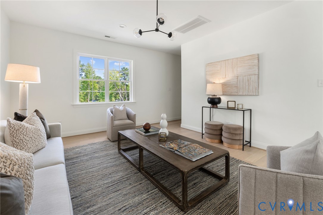 Hardwood-style flooring, white walls, large window with white trim, recessed lighting, and a contemporary chandelier