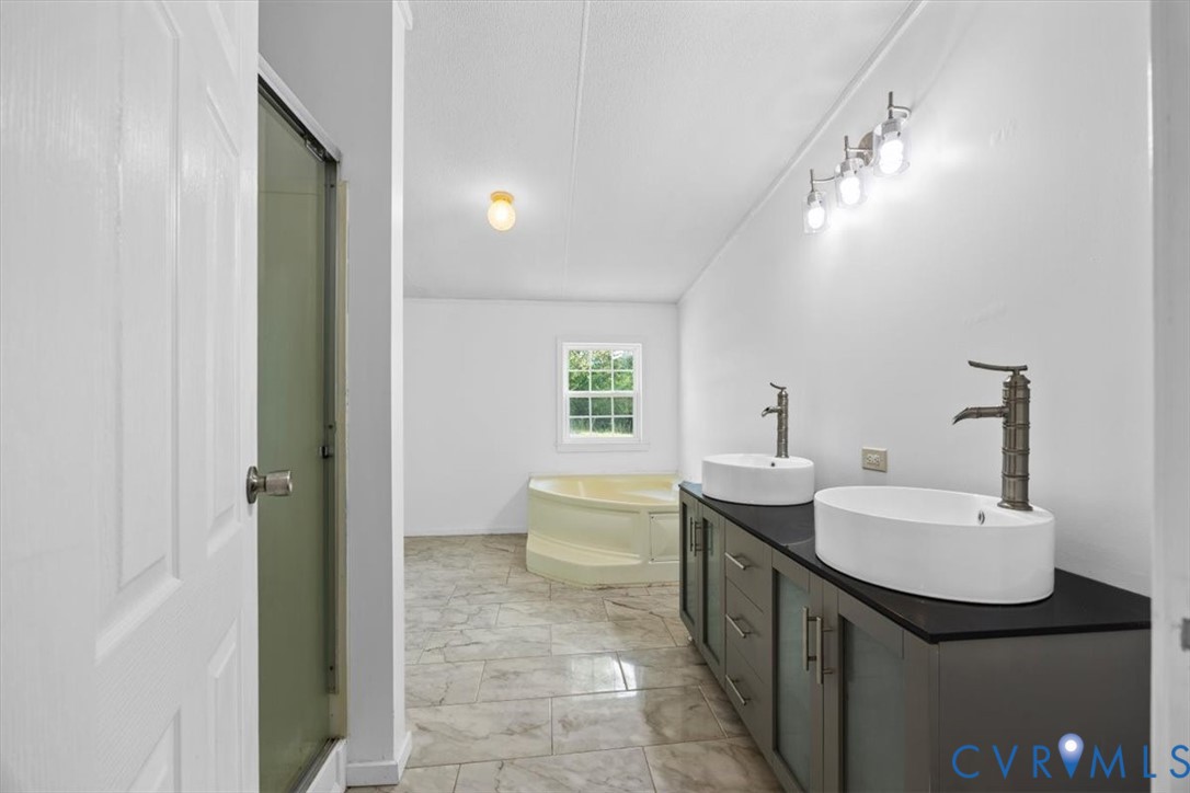 Double vanity with rectangular vessel sinks, matte-finish faucets, dark-toned cabinetry, tile flooring, and a corner soaking tub, separate shower