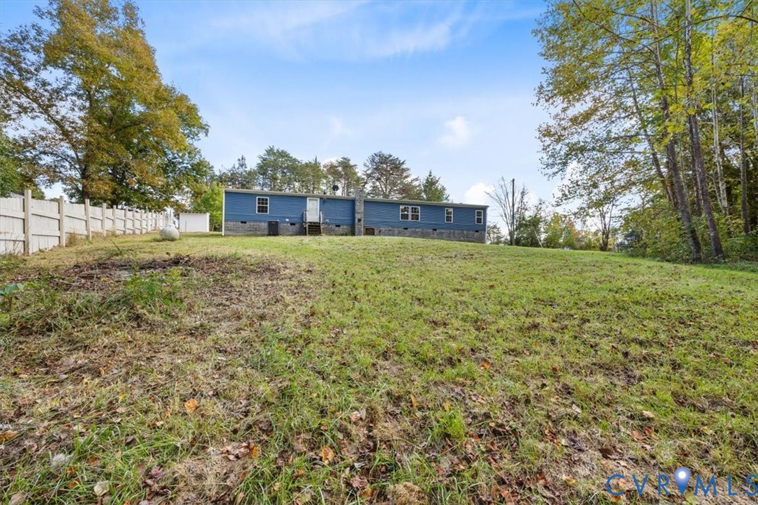 Expansive lot featuring a blue-sided exterior, stone chimney, and perimeter fencing