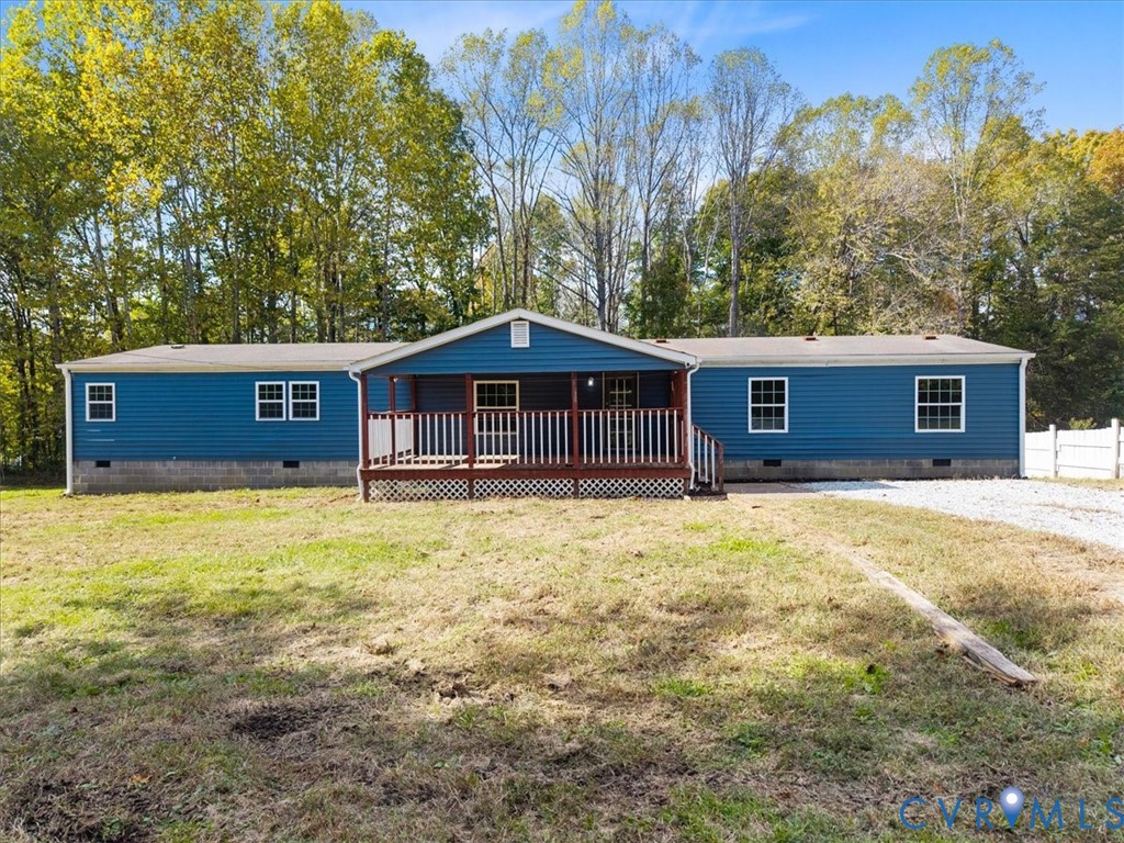 Single-story exterior with blue horizontal siding, front-facing gable roof, concrete block foundation, and covered porch with wooden railings