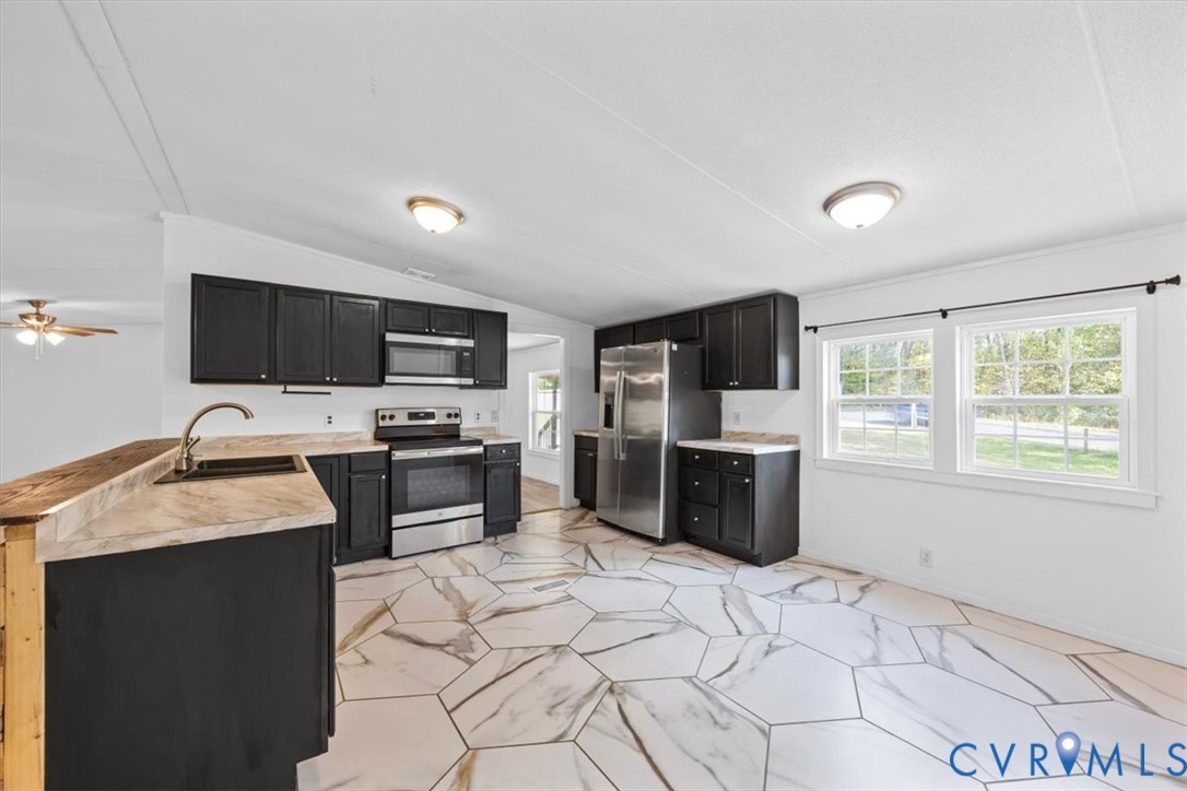 Kitchen featuring dark cabinetry, stainless steel appliances, neutral-toned countertops, and geometric-patterned flooring