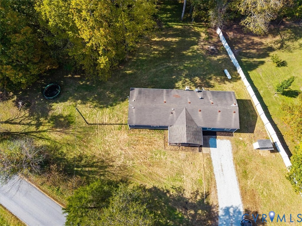 Aerial perspective featuring an expansive lot, gravel driveway, and perimeter fencing