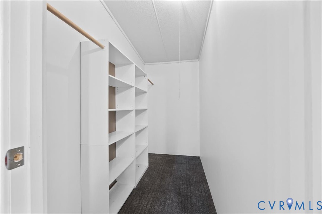 Walk-in closet featuring white built-in shelving and dual hanging rods
