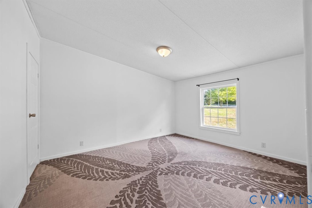 Interior room featuring pattern-textured carpeting, a single-hung window, and a flush-mount ceiling light fixture