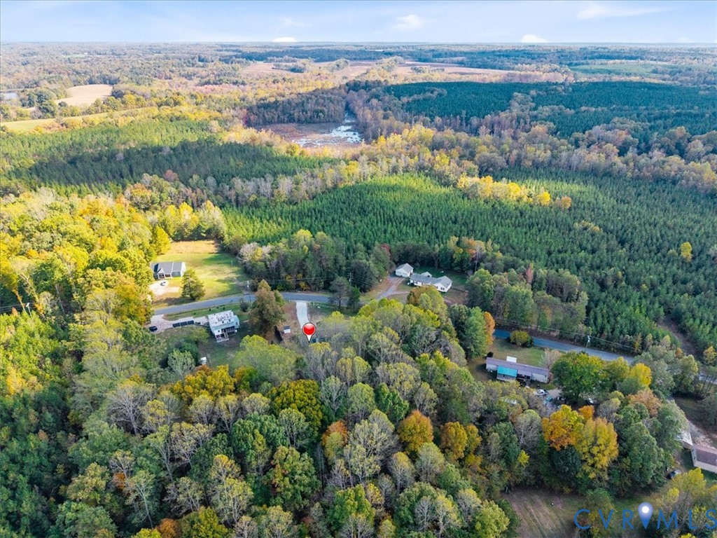 Aerial perspective of property featuring extensive wooded acreage, mature canopy, and asphalt driveway