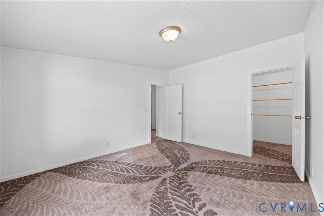 Interior space featuring neutral wall tones, patterned carpeting, flush-mount ceiling lighting, and a closet with built-in shelving