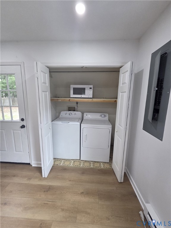 Laundry closet with built-in shelving, wood-finish flooring, and a white paneled door Laundry closet with built-in shelving, wood-finish flooring, and a white paneled door