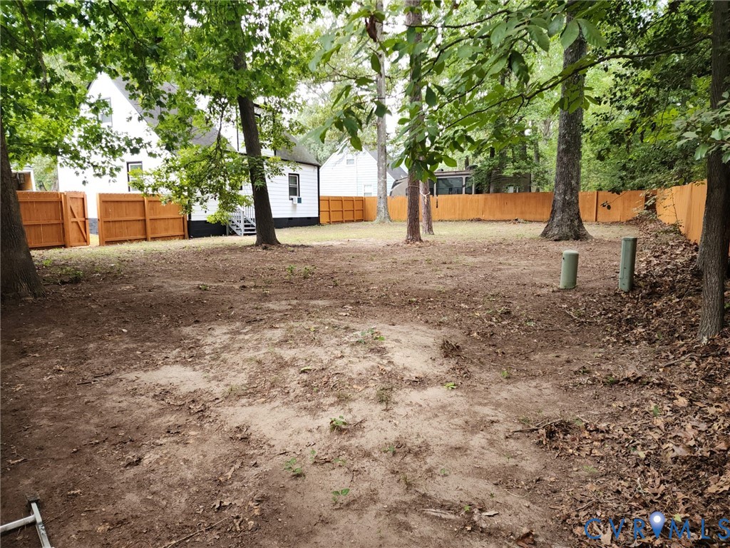 Expansive rear yard featuring mature trees and a wood privacy fence Expansive rear yard featuring mature trees and a wood privacy fence
