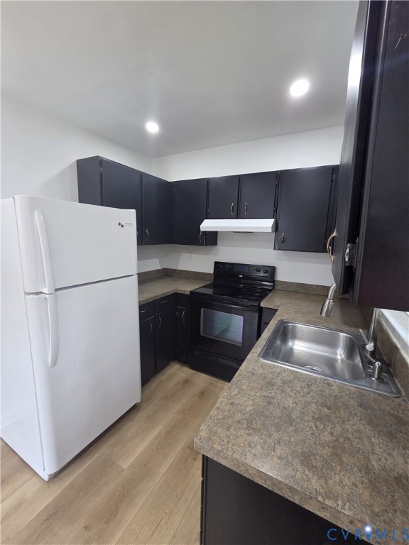 Full kitchen featuring dark cabinetry, L-shaped countertops, wood-finish flooring, and recessed lighting Full kitchen featuring dark cabinetry, L-shaped countertops, wood-finish flooring, and recessed lighting