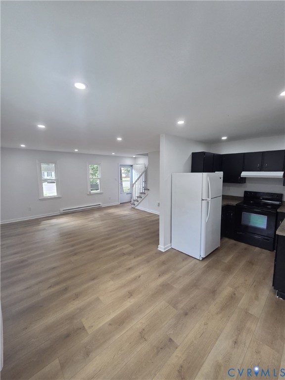 Open-concept living space with wood-finish flooring, recessed lighting, and white walls Open-concept living space with wood-finish flooring, recessed lighting, and white walls